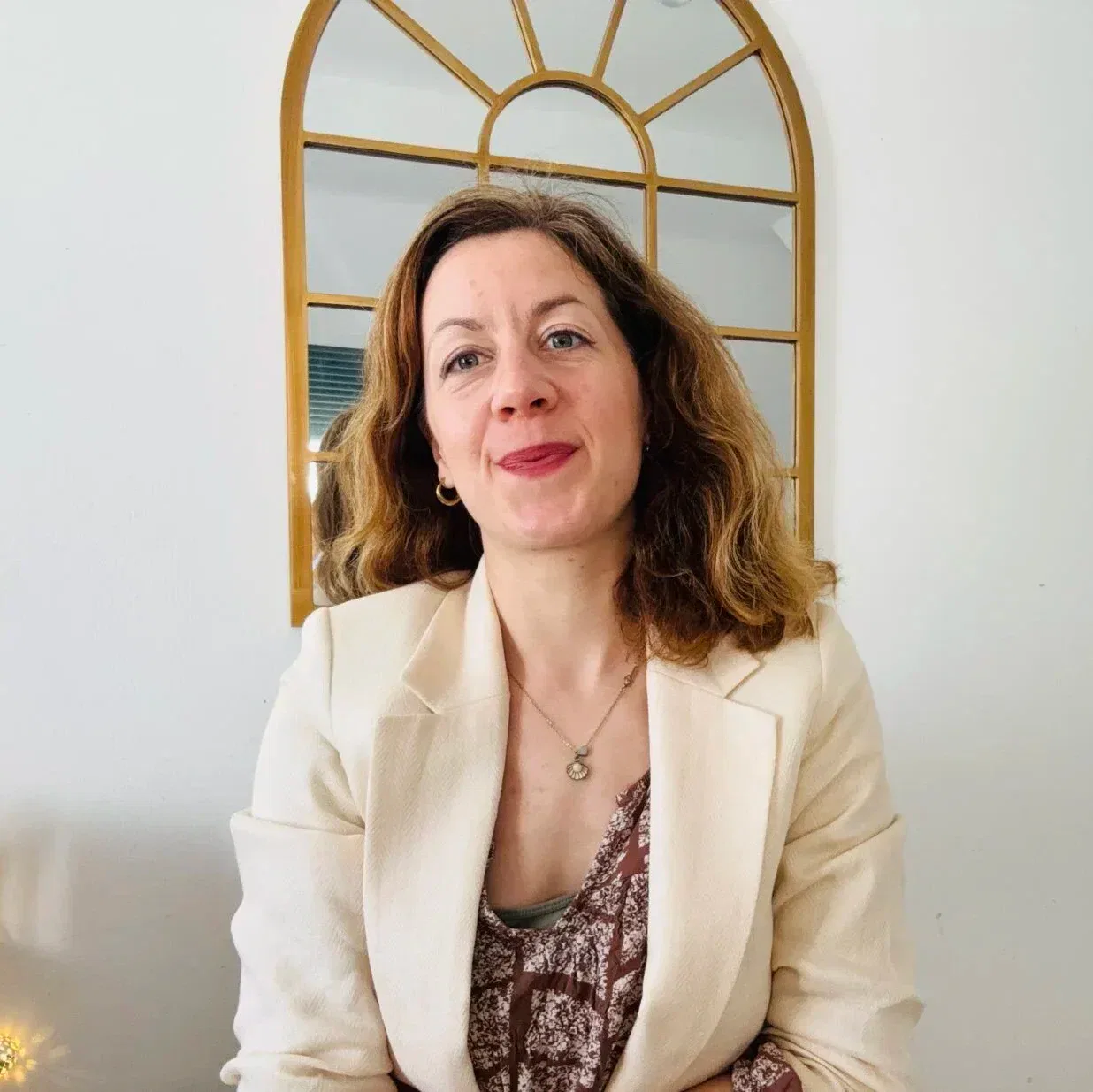Portrait von Emily Wollenweber, Hypnose Coach online, sitzend vor einem Spiegel in hellem Raum